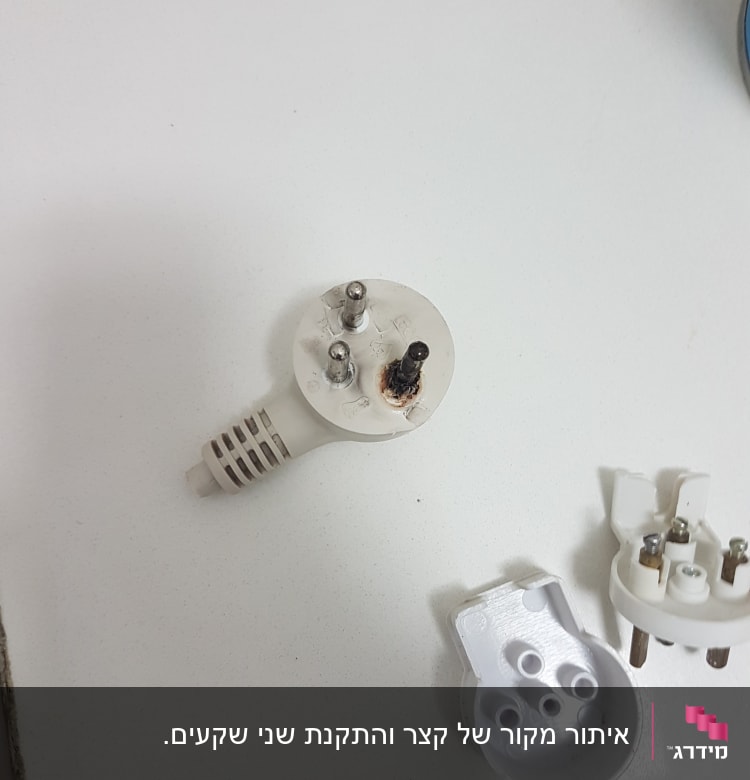 תקע חשמלי שרוף ומפורק על שולחן לבן